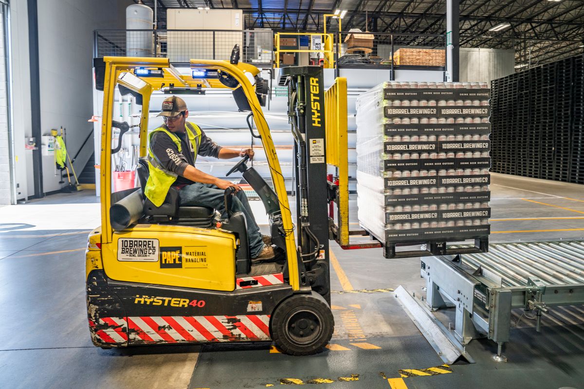 Forklift operator handling pallets inside a logistics warehouse